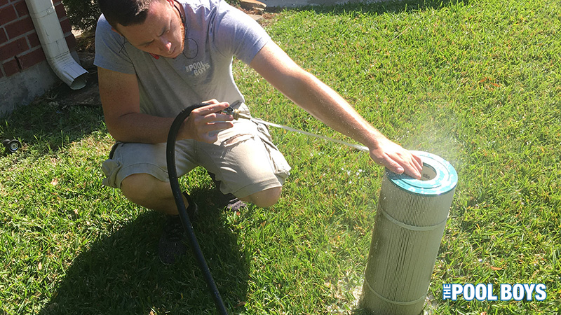 The Pool Boys team member cleaning a pool filter