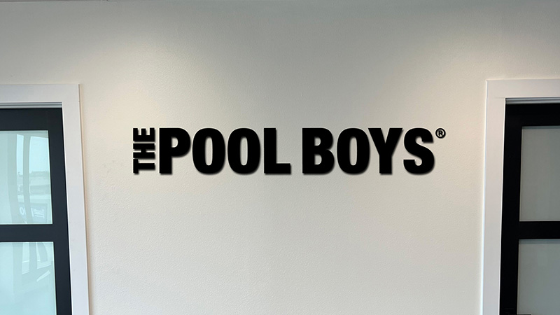 The Pool Boys lobby sign black logo on white wall