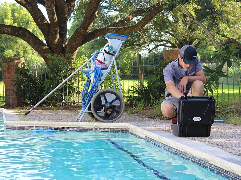 The Pool Boys maintenance technician testing a pool water sample next to a swimming pool.